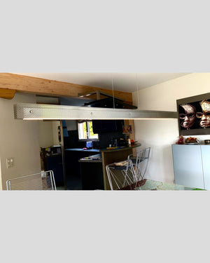 Massgefertigte Hängeleuchte aus Edelstahl-Lochblech mit LED-Technik und höhenverstellbarer Aufhängung in einem stilvollen Wohnraum