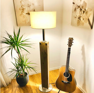 Handgefertigte Stehlampe aus alter Eiche mit indirekter ultrawarmweisser LED-Beleuchtung neben Pflanze und Gitarre in einem stilvollen Wohnraum